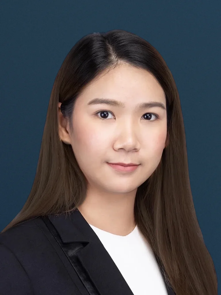 Portrait of an audit partner with long dark hair, wearing a black blazer and white top, against a dark blue background.